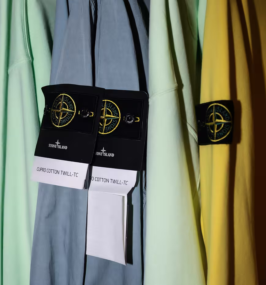 Stone Island garments in pastel colors on clothing rack