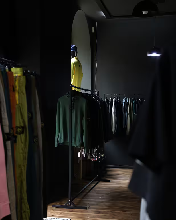 Dark fashion store interior with mirror and clothing racks