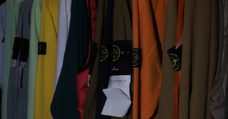 Stone Island garments hanging on rail in various colors, showcasing urban fashion aesthetic