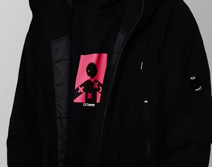 Man wearing black C.P. Company hoodie with graphic print and outerwear