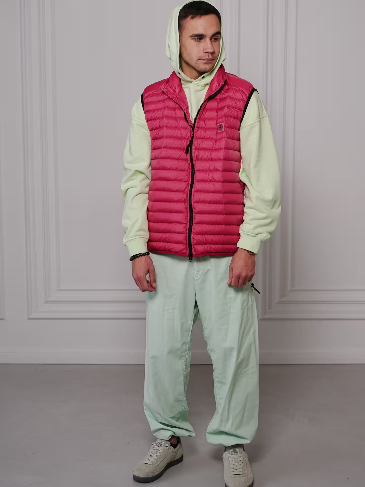 Man wearing red puffer vest with light green outfit in streetwear style